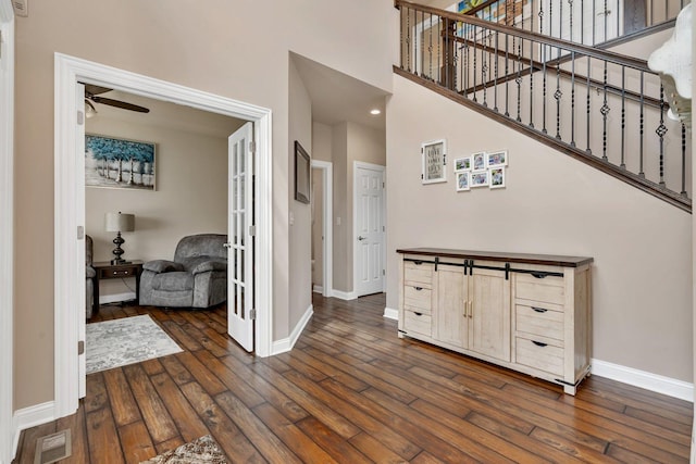 foyer entrance featuring ceiling fan, stairs, baseboards, dark wood-type flooring, and visible vents