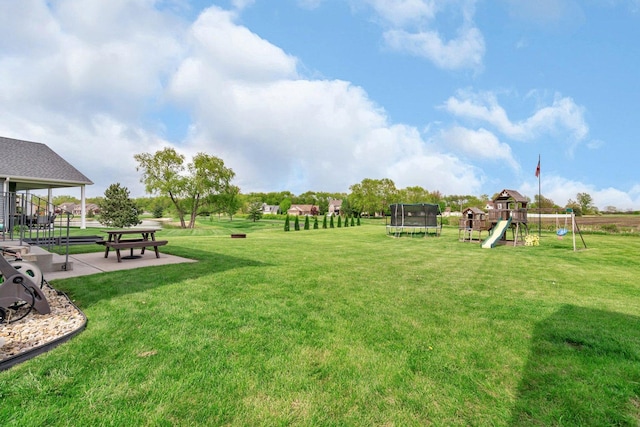 view of community featuring a lawn, a trampoline, a patio, and playground community