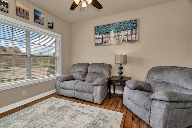 living area featuring baseboards, ceiling fan, and wood finished floors