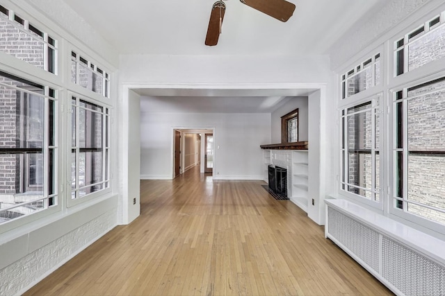 1431 W Rascher Ave Unit 1W, Chicago, IL 60640 - unfurnished living room with radiator heating unit, a ceiling fan, a fireplace, light wood-style flooring, and baseboards