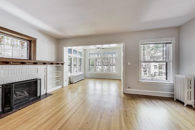 1431 W Rascher Ave Unit 1W, Chicago, IL 60640 - unfurnished living room featuring radiator heating unit, wood finished floors, a brick fireplace, and a ceiling fan