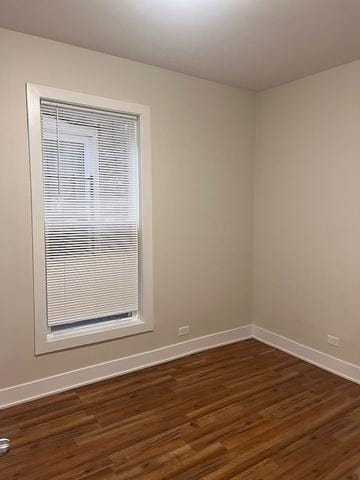 empty room with baseboards and dark wood-type flooring