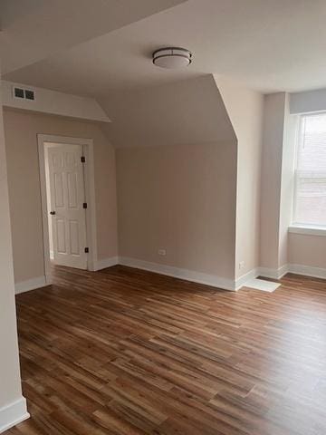 additional living space featuring baseboards, visible vents, wood finished floors, and lofted ceiling