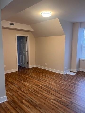 additional living space with baseboards, visible vents, wood finished floors, and lofted ceiling