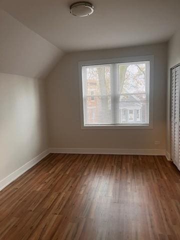 additional living space with baseboards, lofted ceiling, and wood finished floors