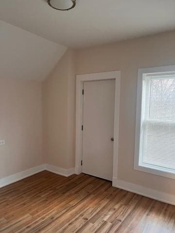 additional living space featuring baseboards, light wood-style flooring, and vaulted ceiling