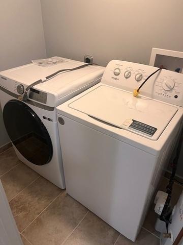 laundry area with laundry area, washer and clothes dryer, and light tile patterned flooring