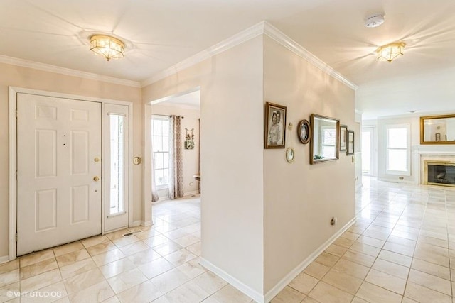 foyer entrance with a glass covered fireplace, baseboards, ornamental molding, and light tile patterned flooring
