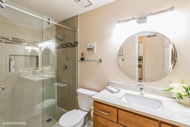 full bathroom with vanity, a shower stall, toilet, and visible vents