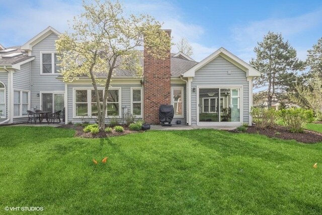 rear view of property with a patio, a chimney, and a yard