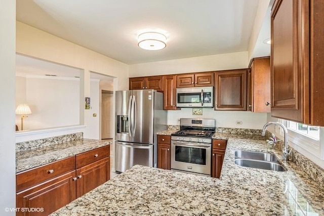 kitchen with light stone counters, a sink, brown cabinetry, and stainless steel appliances