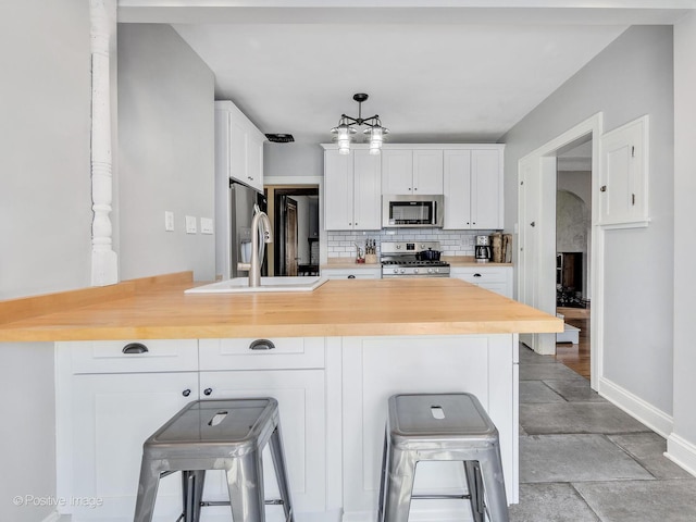 303 Anthony St, Glen Ellyn, IL 60137 - kitchen with stainless steel appliances, a peninsula, tasteful backsplash, white cabinetry, and a breakfast bar