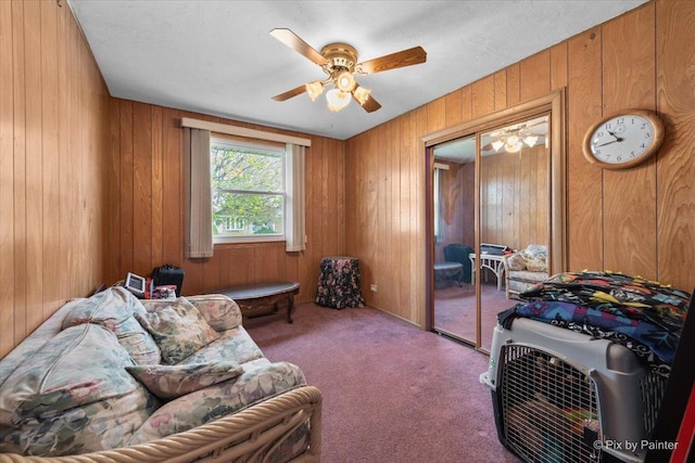 living area featuring wooden walls, carpet, and a ceiling fan