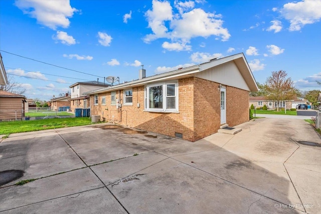 view of side of property with brick siding, fence, crawl space, and a patio