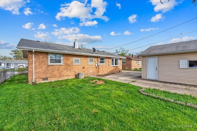 rear view of property with fence, brick siding, central AC unit, a patio, and a yard