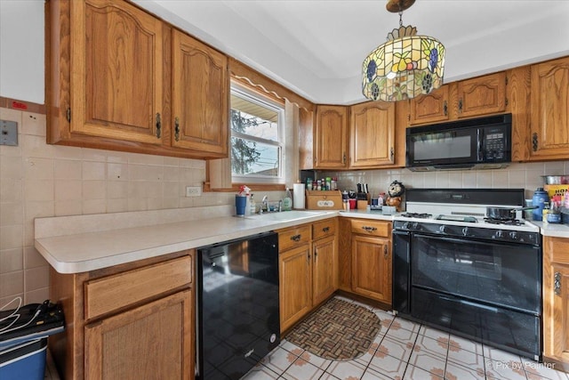 kitchen featuring brown cabinetry, decorative backsplash, light countertops, a sink, and black appliances