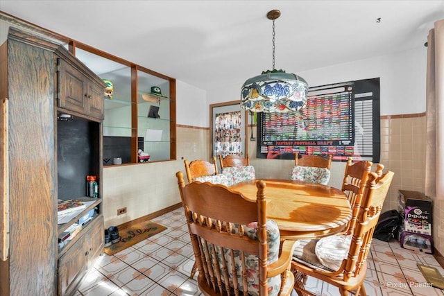 dining room with light floors, a wainscoted wall, and tile walls
