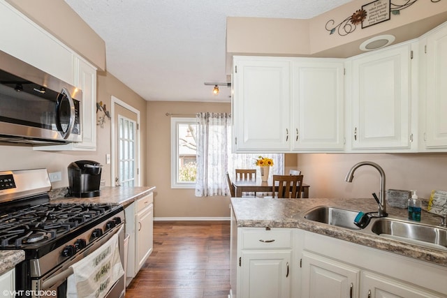 kitchen featuring a sink, stainless steel appliances, white cabinetry, and wood finished floors