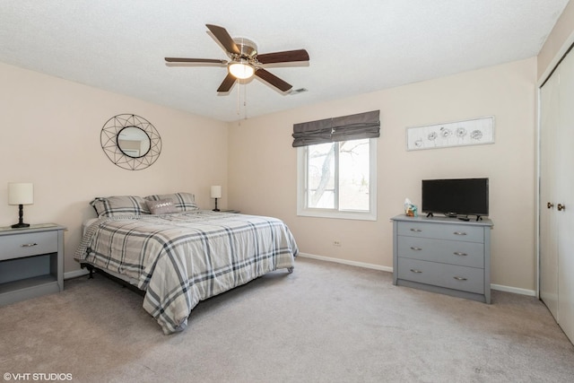 bedroom featuring light colored carpet, a closet, baseboards, and a ceiling fan