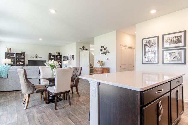 kitchen with light countertops, light wood-style flooring, a kitchen island, and dark brown cabinets