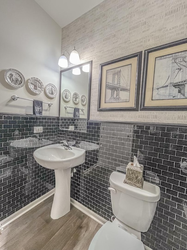 half bathroom with toilet and wood finished floors