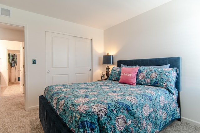 carpeted bedroom featuring baseboards, visible vents, and a closet