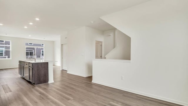 kitchen featuring baseboards, a sink, light wood finished floors, and light countertops