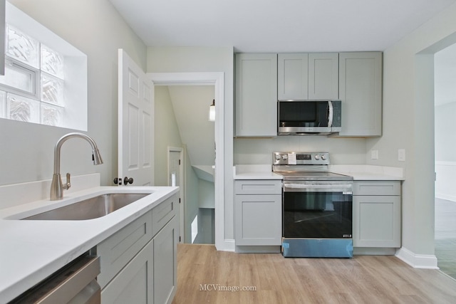 8907 S Luella Ave, Chicago, IL 60617 - kitchen with stainless steel appliances, a sink, gray cabinets, light wood-type flooring, and light countertops