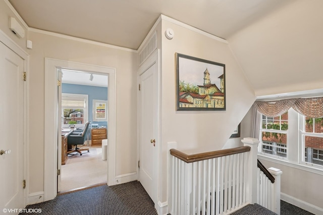 hall featuring a healthy amount of sunlight, baseboards, dark carpet, and an upstairs landing