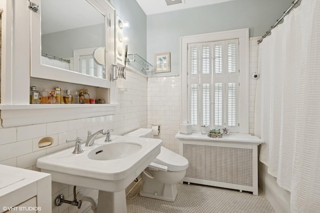 full bathroom with shower / bath combo, toilet, tile patterned floors, radiator, and tile walls