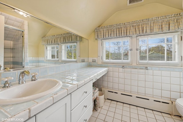 bathroom featuring tile patterned flooring, a baseboard heating unit, vaulted ceiling, and tile walls