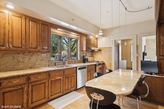 kitchen featuring a sink, light stone countertops, stainless steel appliances, and brown cabinets