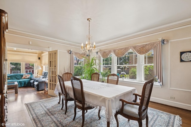 dining room featuring crown molding, baseboards, wood finished floors, and a notable chandelier