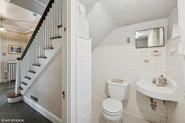 bathroom with visible vents, a sink, toilet, radiator heating unit, and wallpapered walls