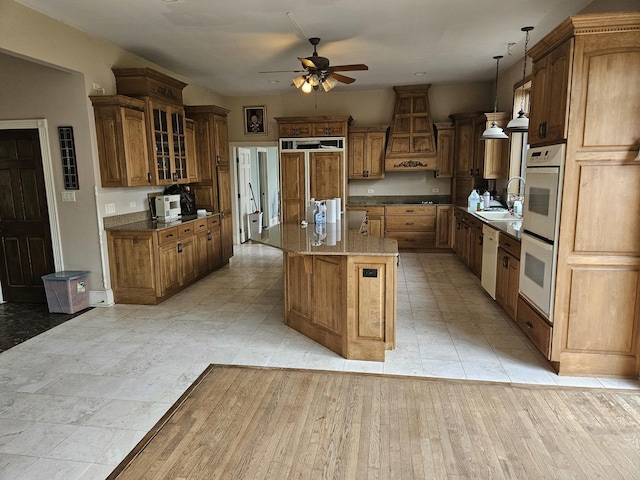 6554 N 16000e Rd, Grant Park, IL 60940 - kitchen featuring a ceiling fan, a sink, brown cabinetry, custom exhaust hood, and a kitchen island