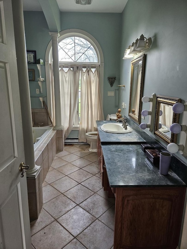 6554 N 16000e Rd, Grant Park, IL 60940 - bathroom featuring toilet, tiled bath, double vanity, decorative columns, and tile patterned flooring
