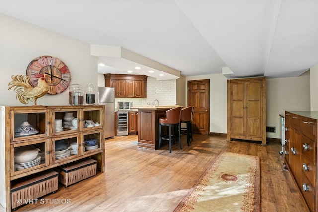 42W142 Ravine Dr, Saint Charles, IL 60175 - interior space featuring a kitchen breakfast bar, beverage cooler, light wood-style flooring, freestanding refrigerator, and brown cabinets