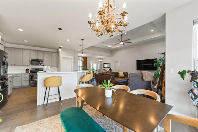 840 Coventry Cir N, Sycamore, IL 60178 - dining space featuring a raised ceiling, light wood finished floors, recessed lighting, and ceiling fan with notable chandelier