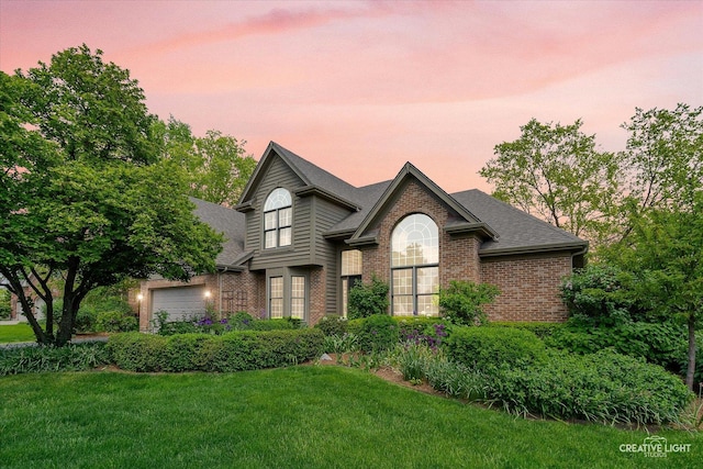 traditional-style house featuring brick siding, a lawn, and roof with shingles