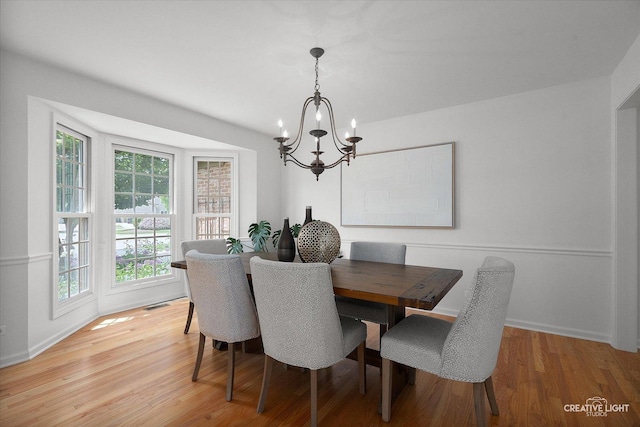dining room with a chandelier, light wood finished floors, and baseboards