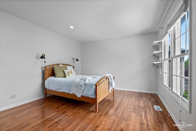 bedroom with wood finished floors, baseboards, and recessed lighting