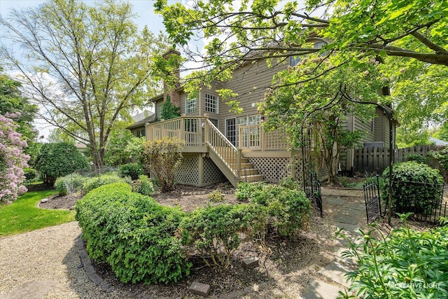 back of property with stairway, fence, a wooden deck, and a chimney