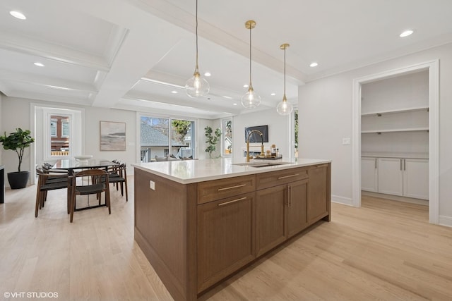 kitchen featuring a sink, light countertops, pendant lighting, and light wood-type flooring