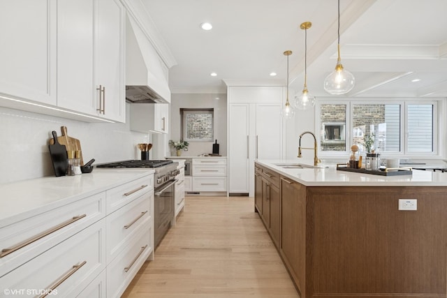 kitchen with stainless steel stove, a sink, crown molding, and white cabinets