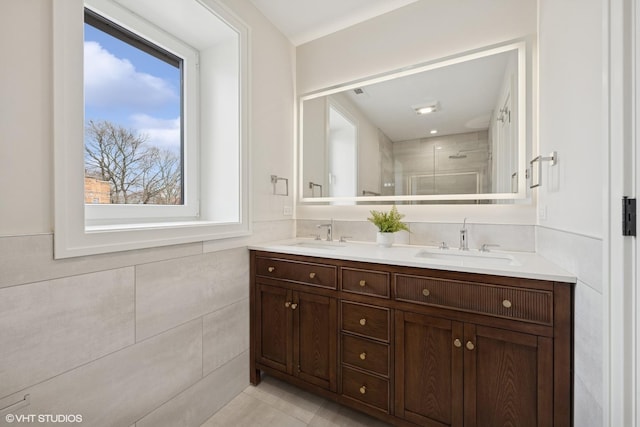 full bath featuring a sink, tile walls, walk in shower, and double vanity