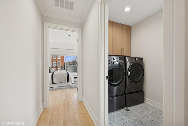 clothes washing area with cabinet space, crown molding, baseboards, visible vents, and washing machine and dryer