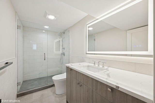 bathroom featuring tile patterned flooring, vanity, toilet, tile walls, and a stall shower