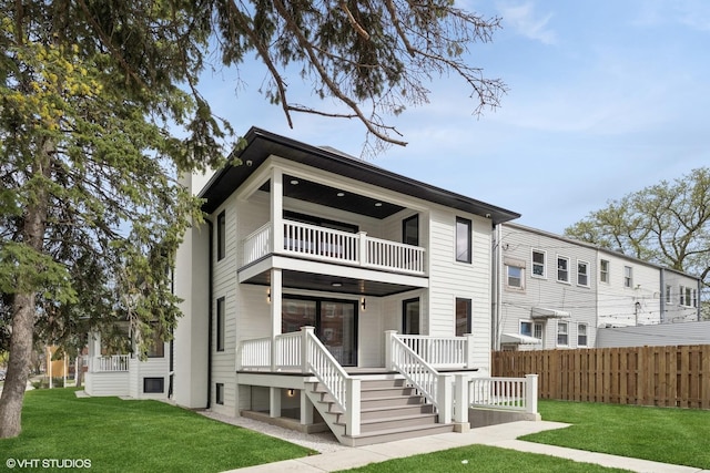 rear view of house with a lawn, fence, a balcony, and a porch