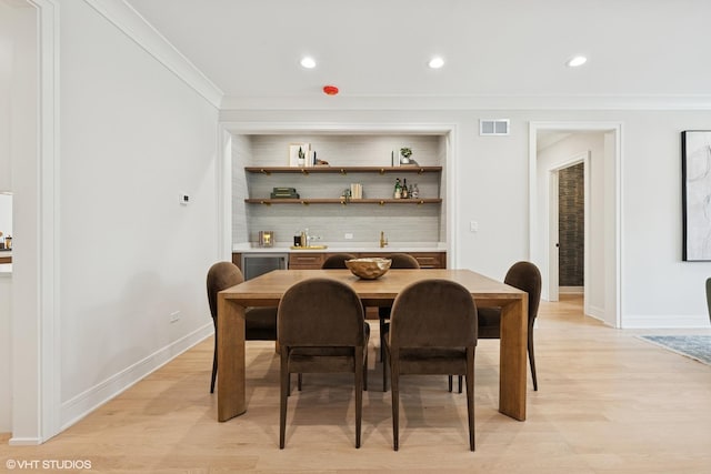 dining area featuring crown molding, baseboards, visible vents, and light wood finished floors
