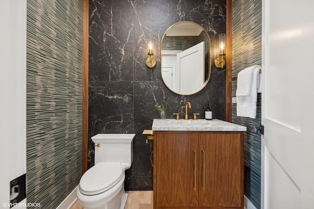 half bath with toilet, tile walls, and vanity
